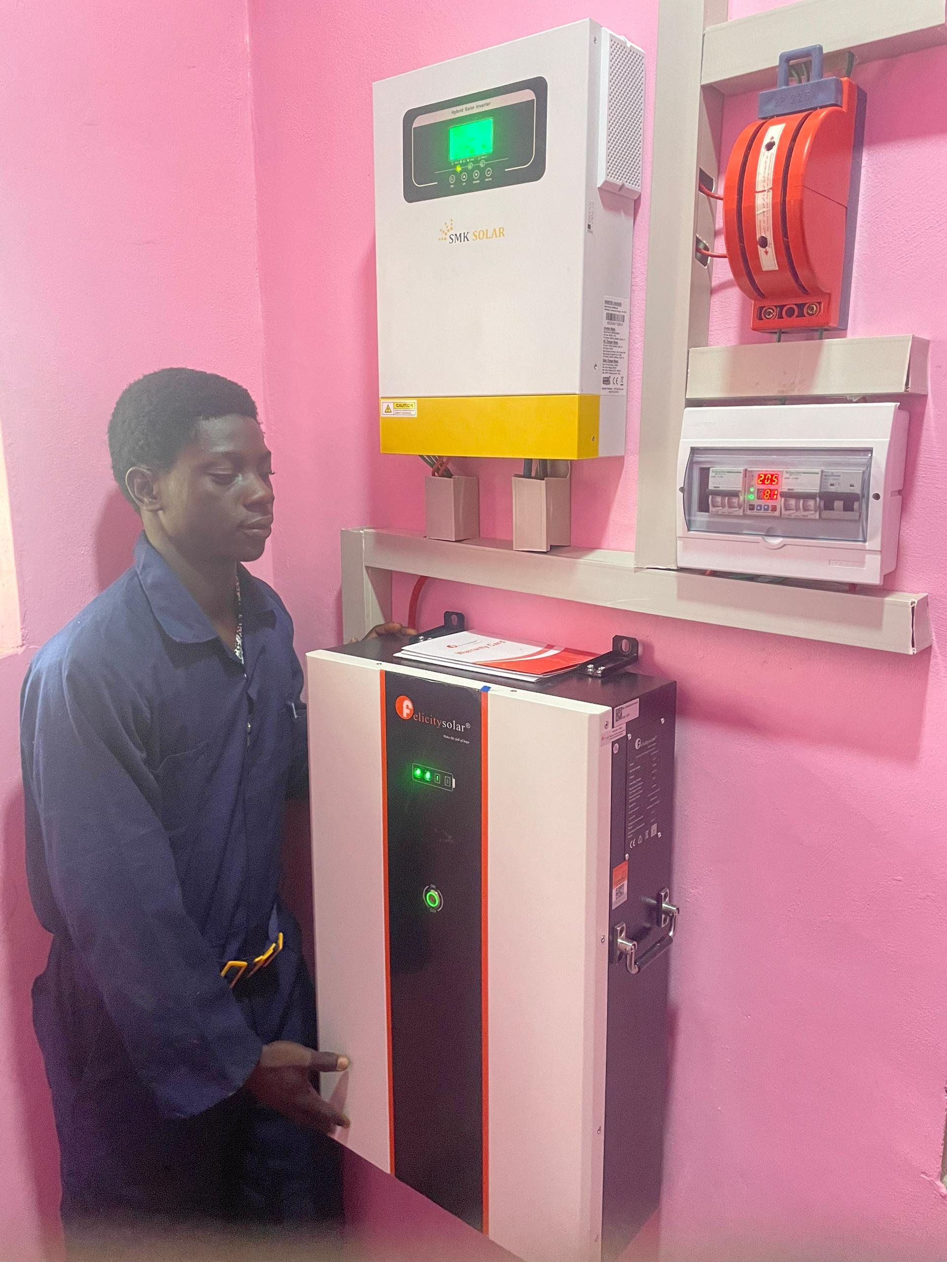 Ramlad Global Technologies engineer standing with a Chrisolar inverter and battery bank system.